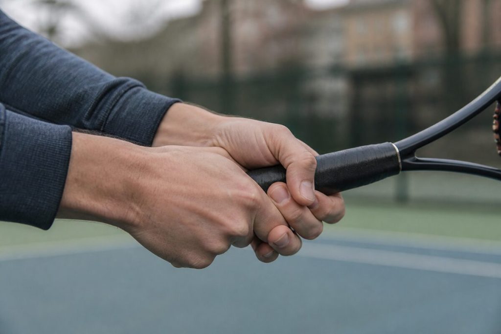 Close-up of hands gripping a tennis racket outdoors